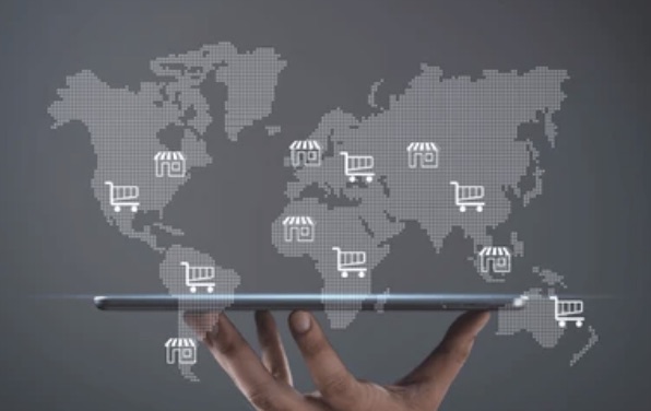 Hand holding a tablet with a world map and shopping carts — global cross-border eCommerce
