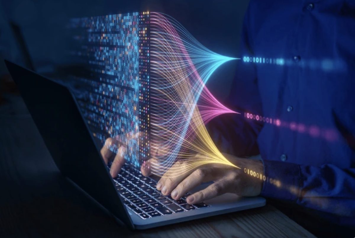 Hands typing on a laptop with colorful data streams flowing out of the screen — an AI commerce lab