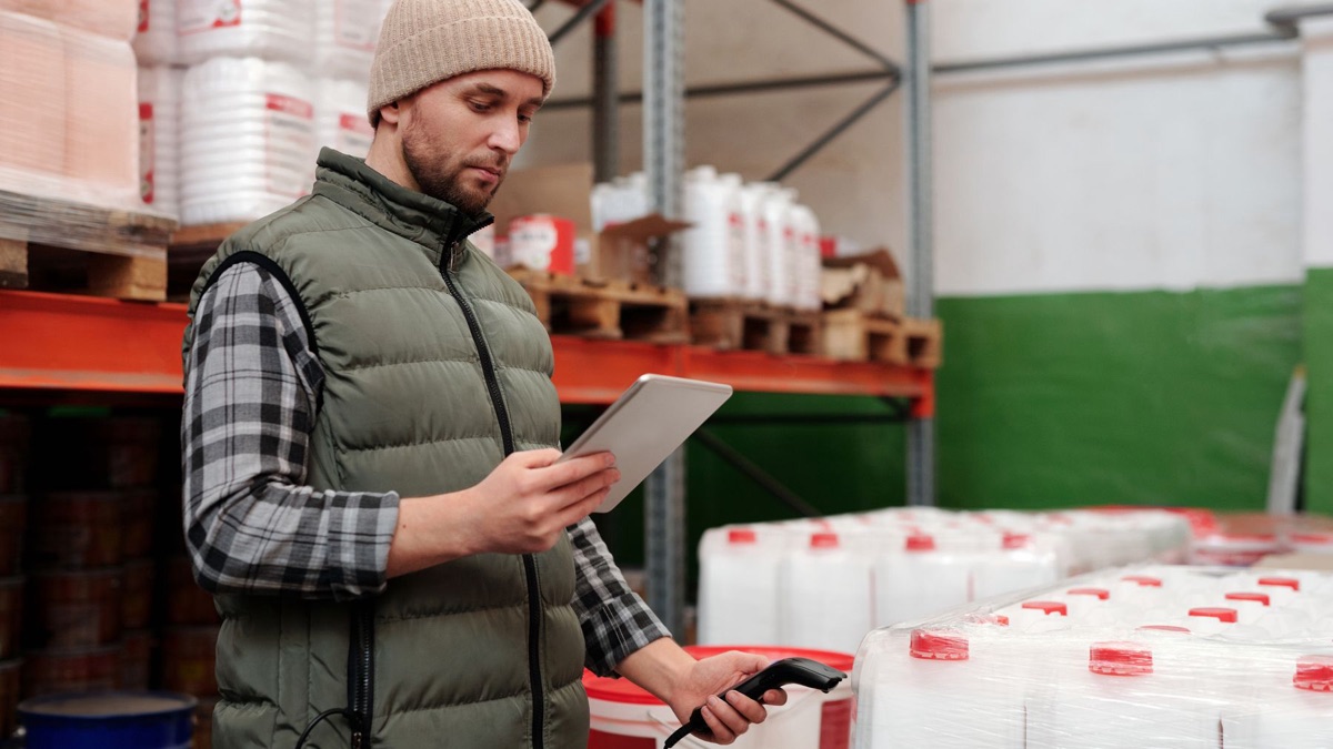 A B2B distributor checks inventory on a tablet in a warehouse, a connected wholesale commerce operation